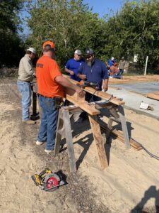 Golden Crescent Habitat for Humanity volunteer using a power saw to cut lumber at a new home construction site