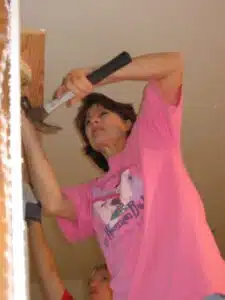 Habitat for Humanity Women Build volunteer in a pink shirt using a hammer during a home construction project